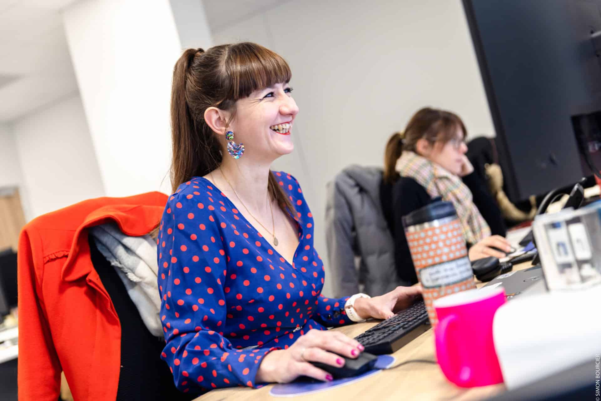 Portrait d'une collaboratrice souriante assise dans les bureaux de l'agence Winbound