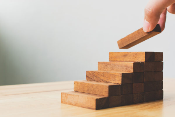 Mains arrangeant l'empilage des blocs de bois comme escalier. Concept des fondamentaux de l'ABM et du marketing BtoB pour améliorer la croissance de l'entreprise