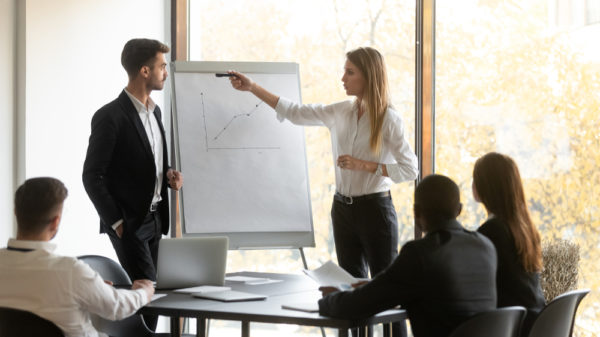 deux personnes présentent une stratégie devant un groupe d'individus dans une salle de réunion